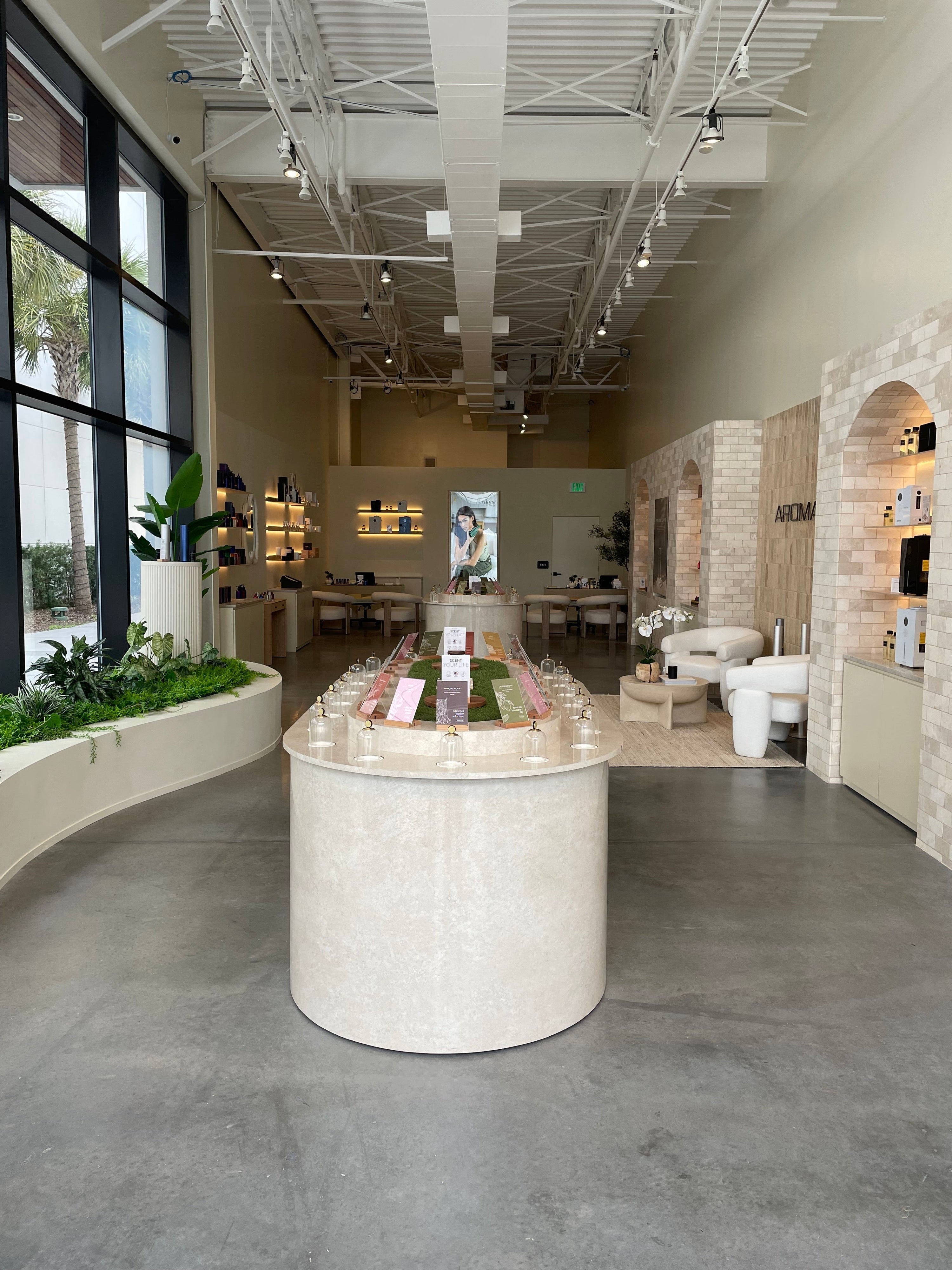 A view of the Aroma360 Jacksonville showroom, highlighting modern furniture, plants, and the spacious, high-ceilinged interior. 